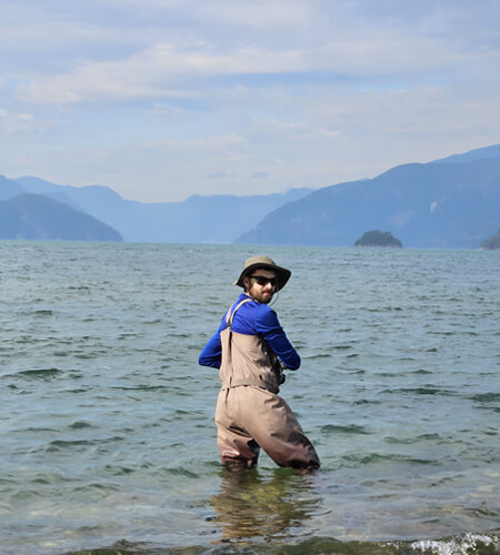 Reel fly fishers founder fishing in ocean with blue shadowy mountains in the background